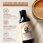 A bottle of Vallee de Galene Chicory Root concentrate with Elderberry is laying on a table next to glass with foamy chicory beverage.