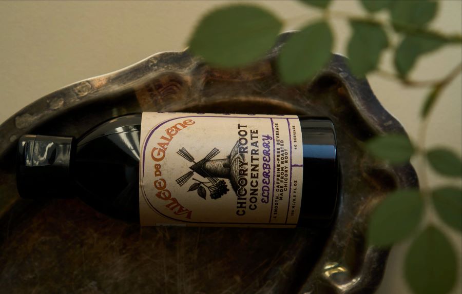 a bottle of chicory root concentrate with elderberry is laying on a bronze tray